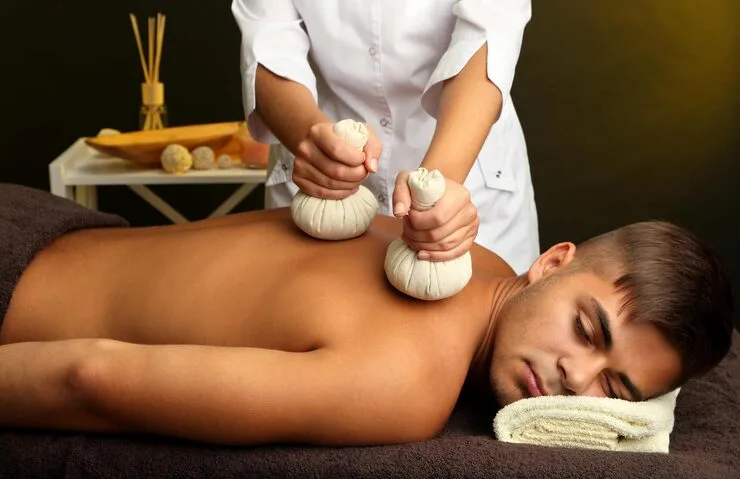 Herbal leaf poultice therapy with warm oil to reduce joint pain, control inflammation, relieve muscle stiffness, and promote healing through deep tissue massage, ideal for arthritis and musculoskeletal discomfort.